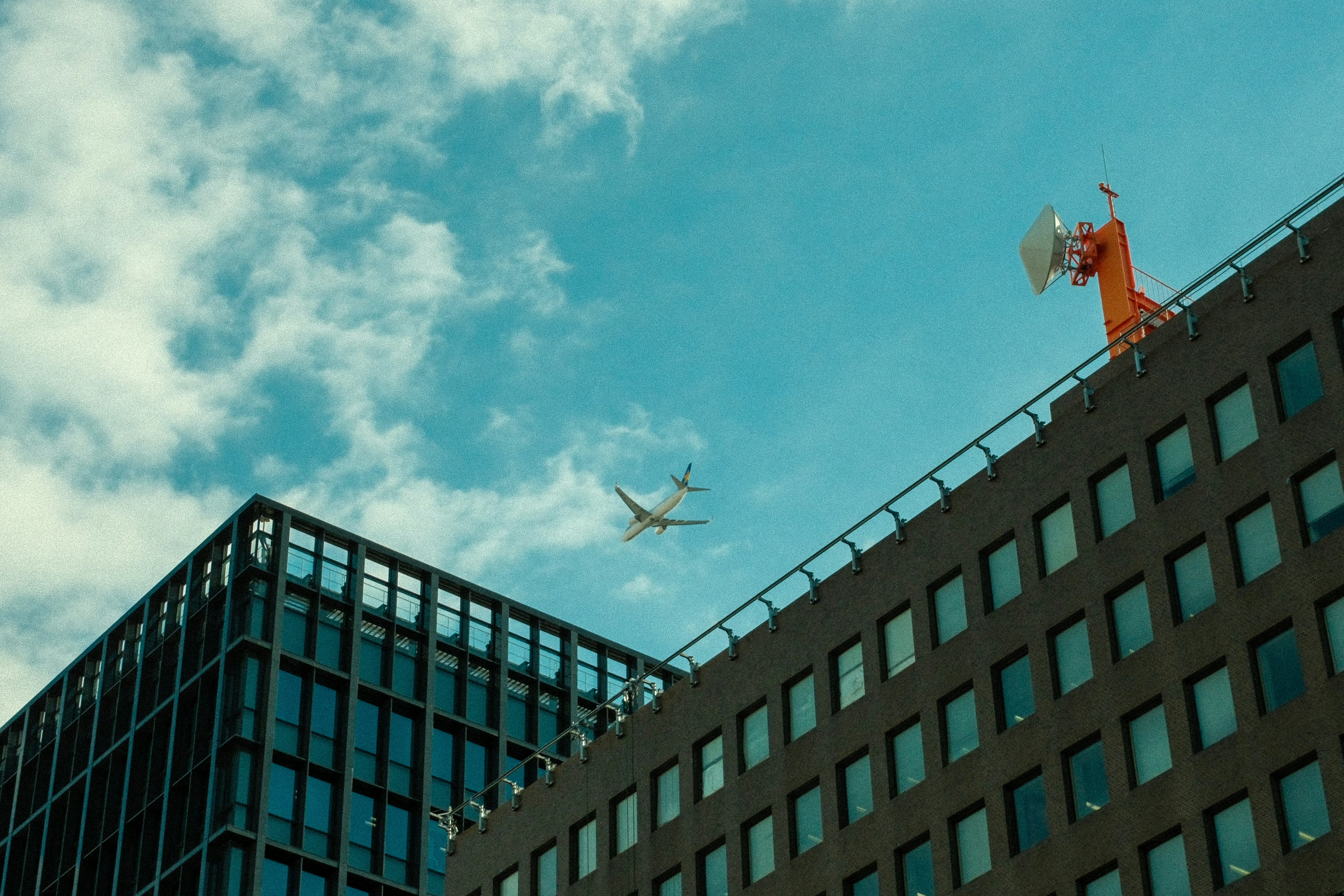 An airplane flying over a tall building with windows, 