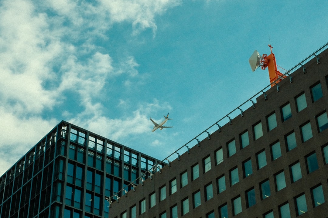 An airplane flying over a tall building with windows,