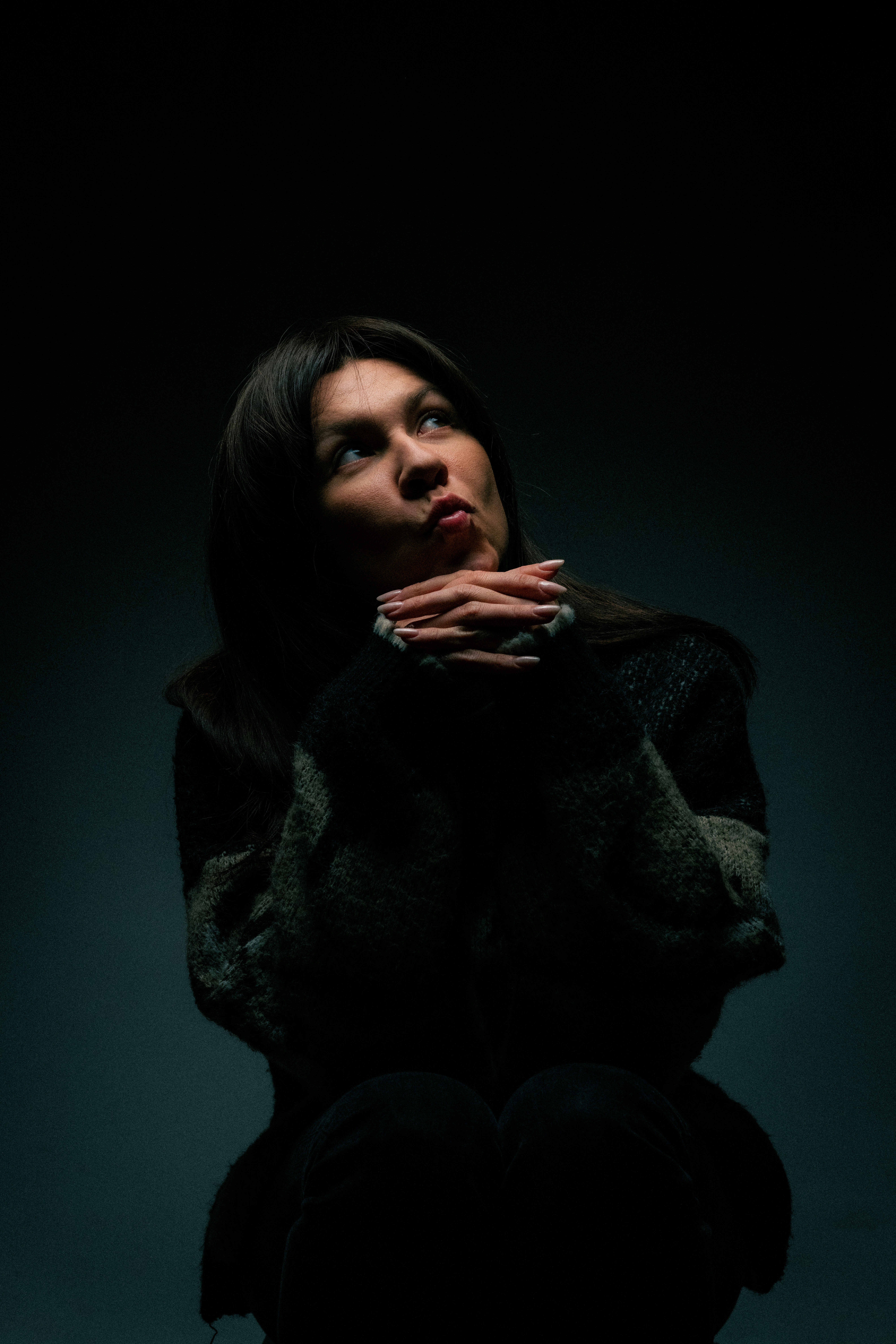 A woman sitting in the dark with her hands on her chest photo – Free ...