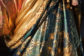 A close up of a woman wearing a gold and blue dress