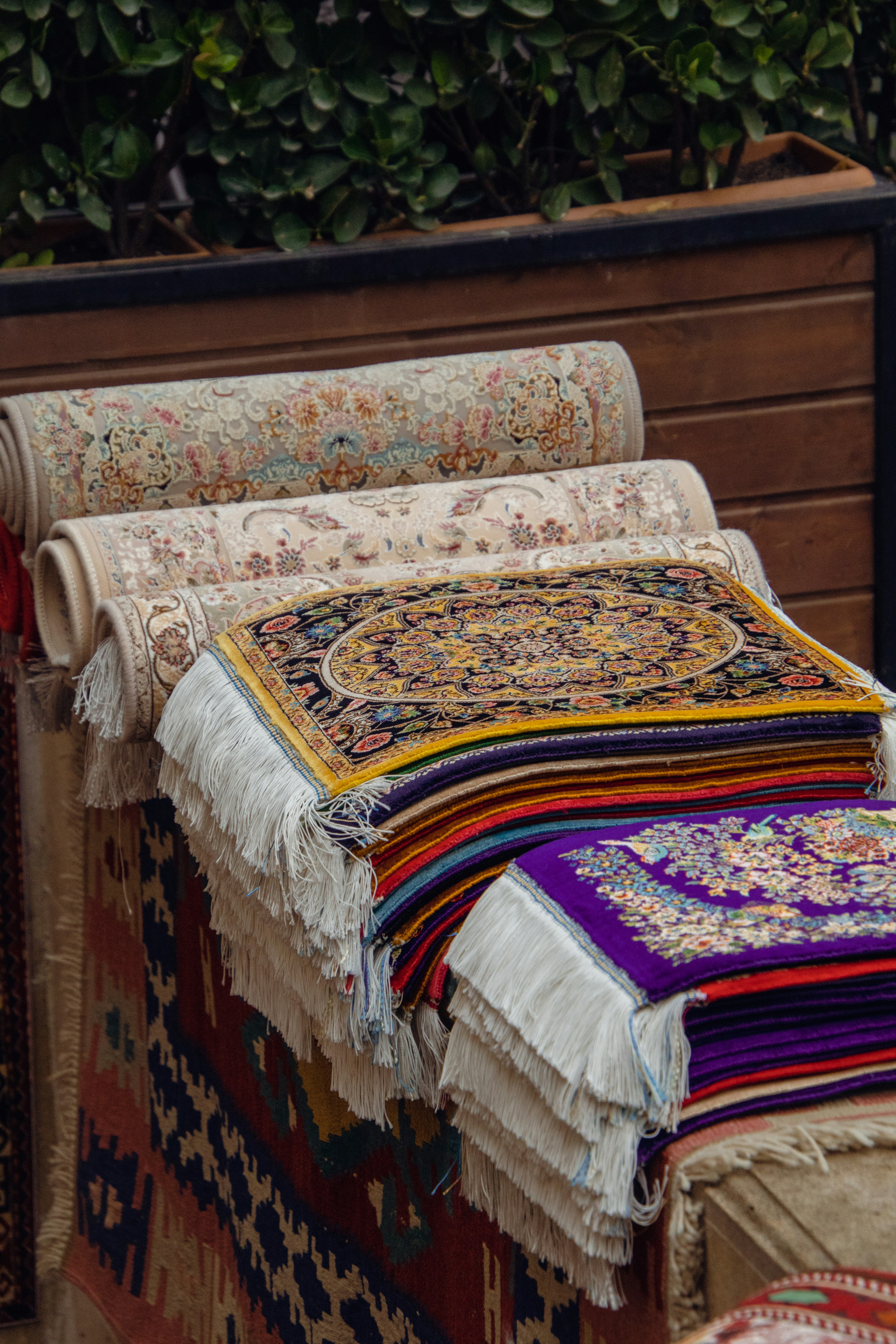 A pile of rugs sitting on top of a wooden bench