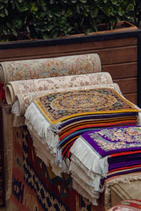 A pile of rugs sitting on top of a wooden bench