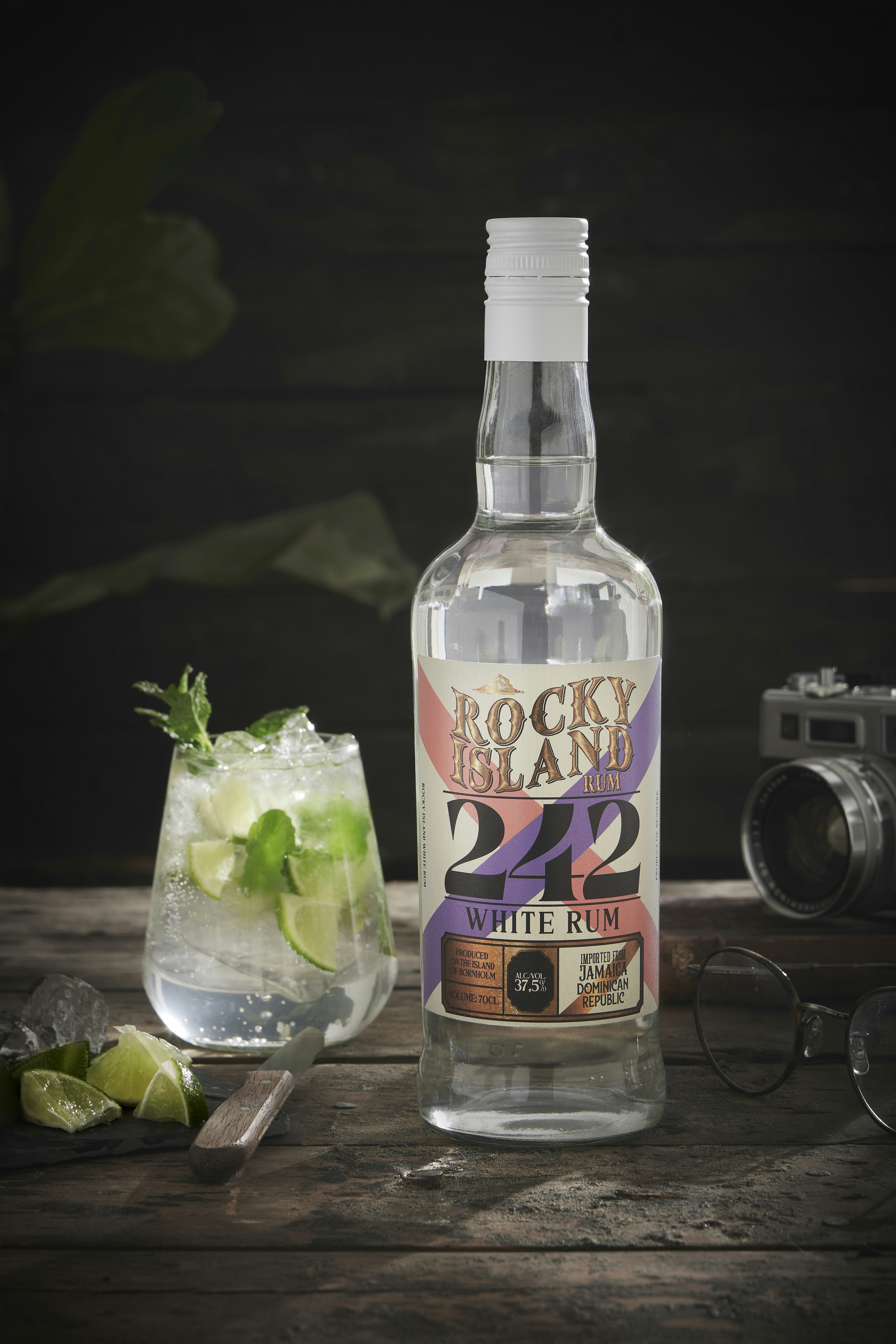 A bottle of vodka next to a glass and a camera