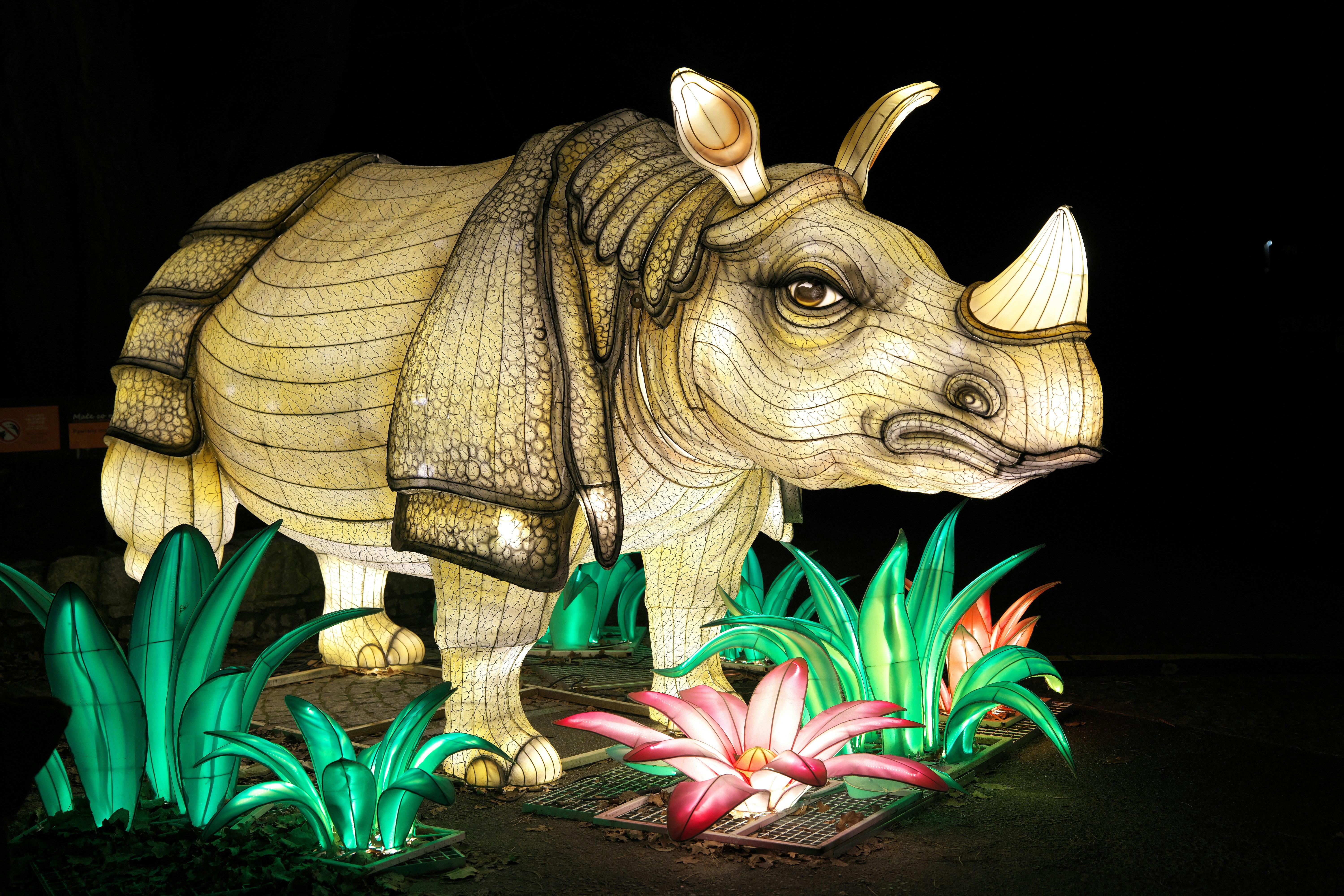 A statue of a rhino standing in a field of flowers