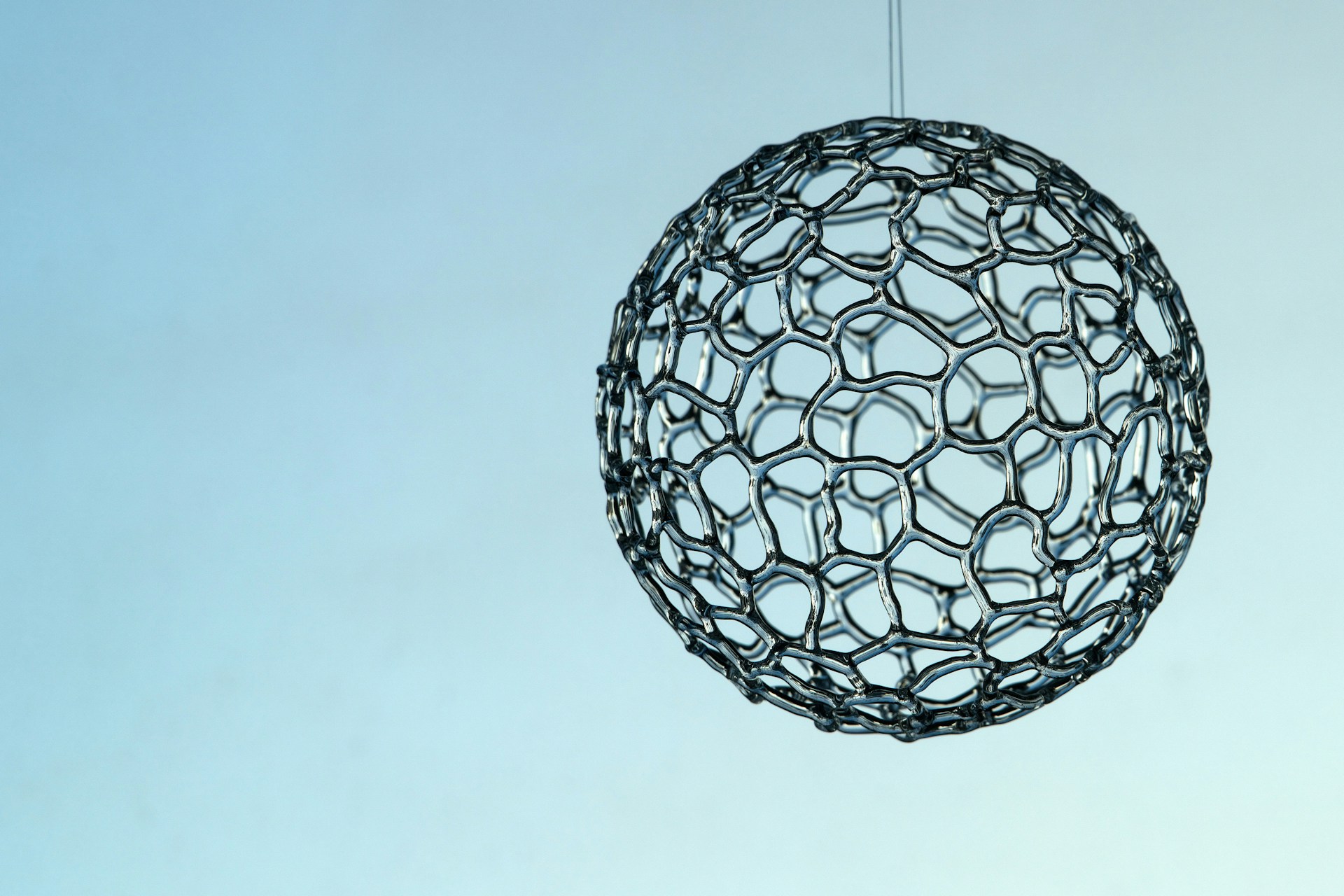 A metal ball hanging from a string in the sky