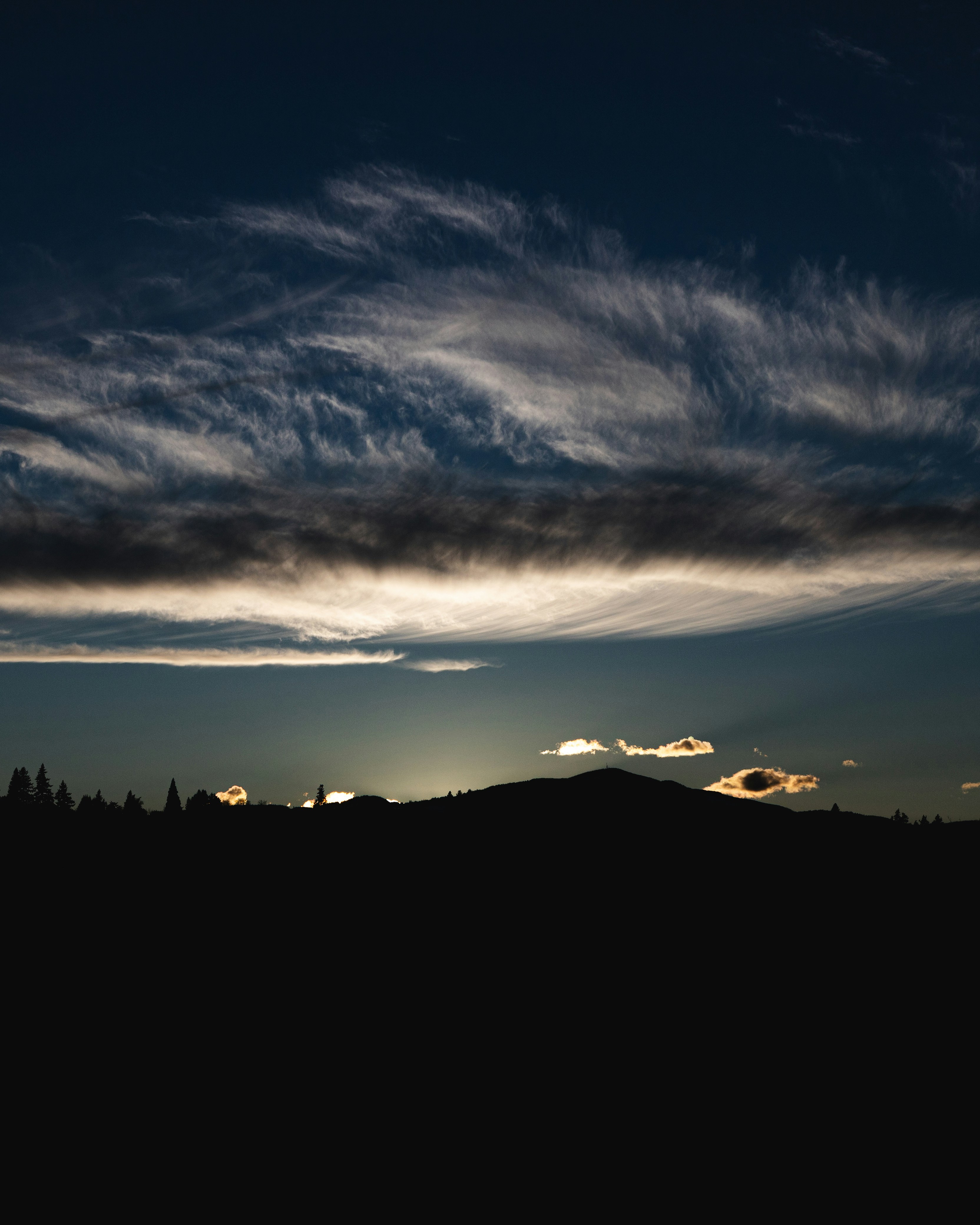 The sun is setting over a mountain with clouds in the sky