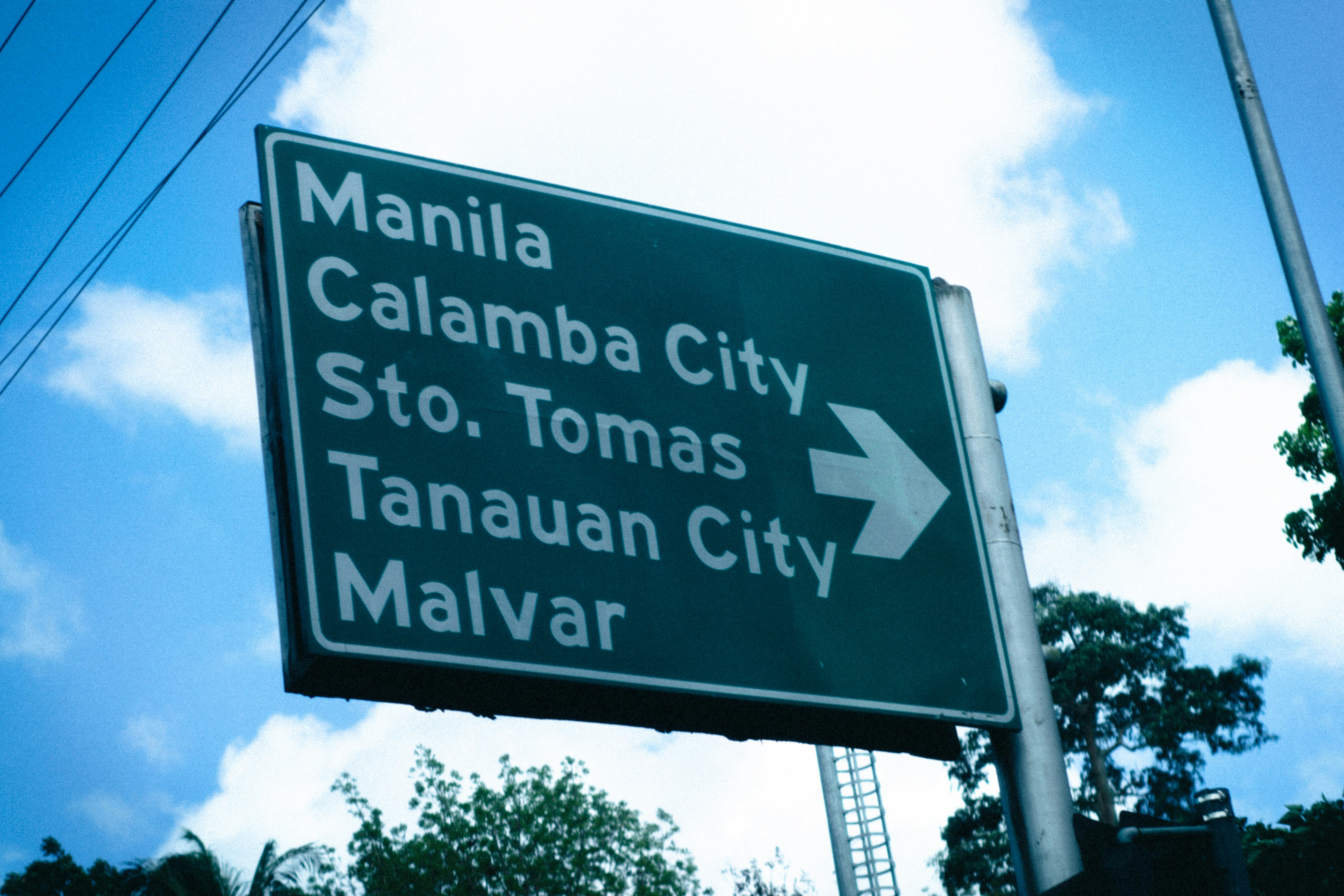 A green and white street sign on the side of a road