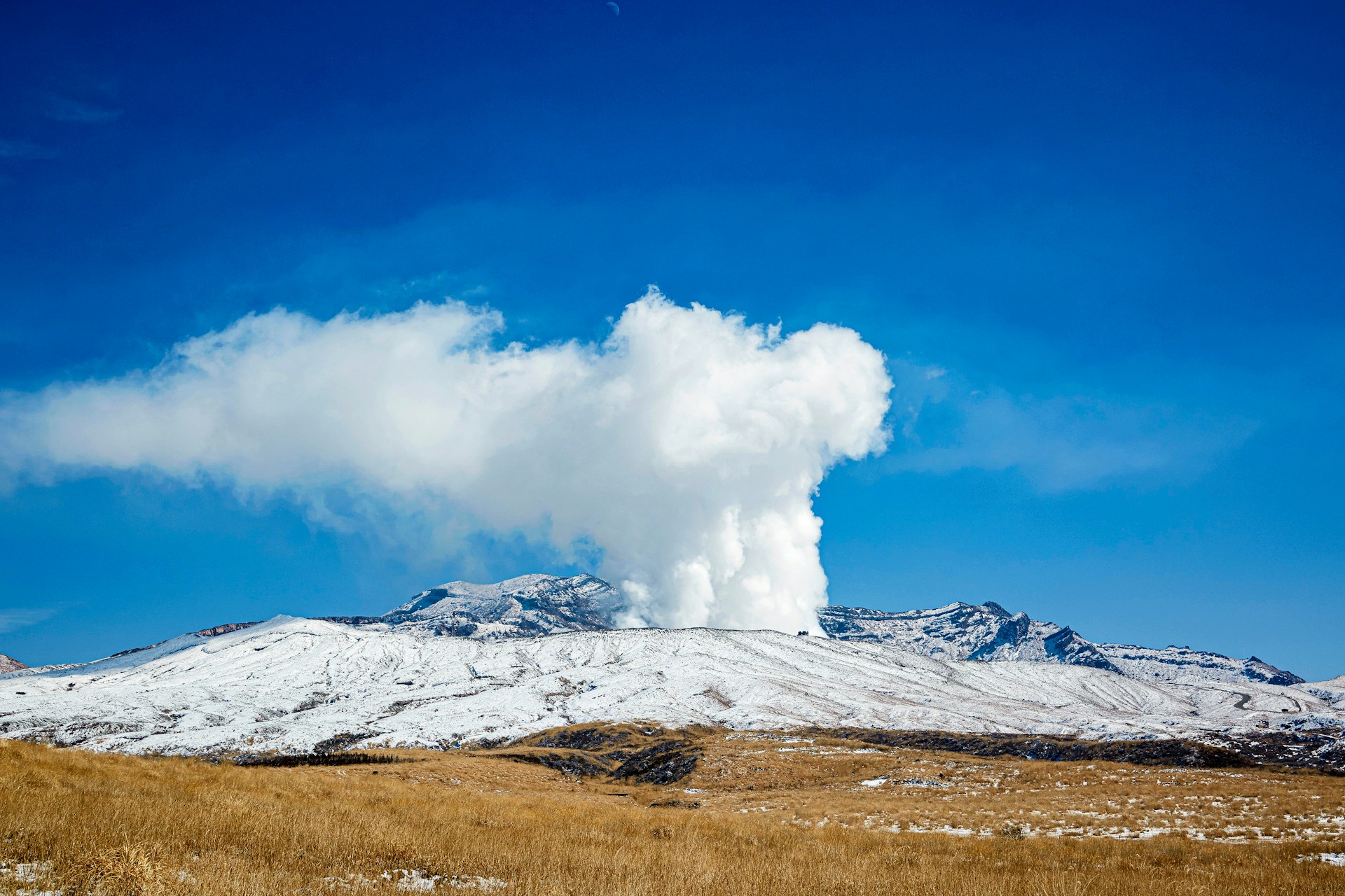 A snow covered mountain with a cloud in the sky