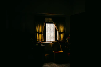 A dark room with a chair and a window