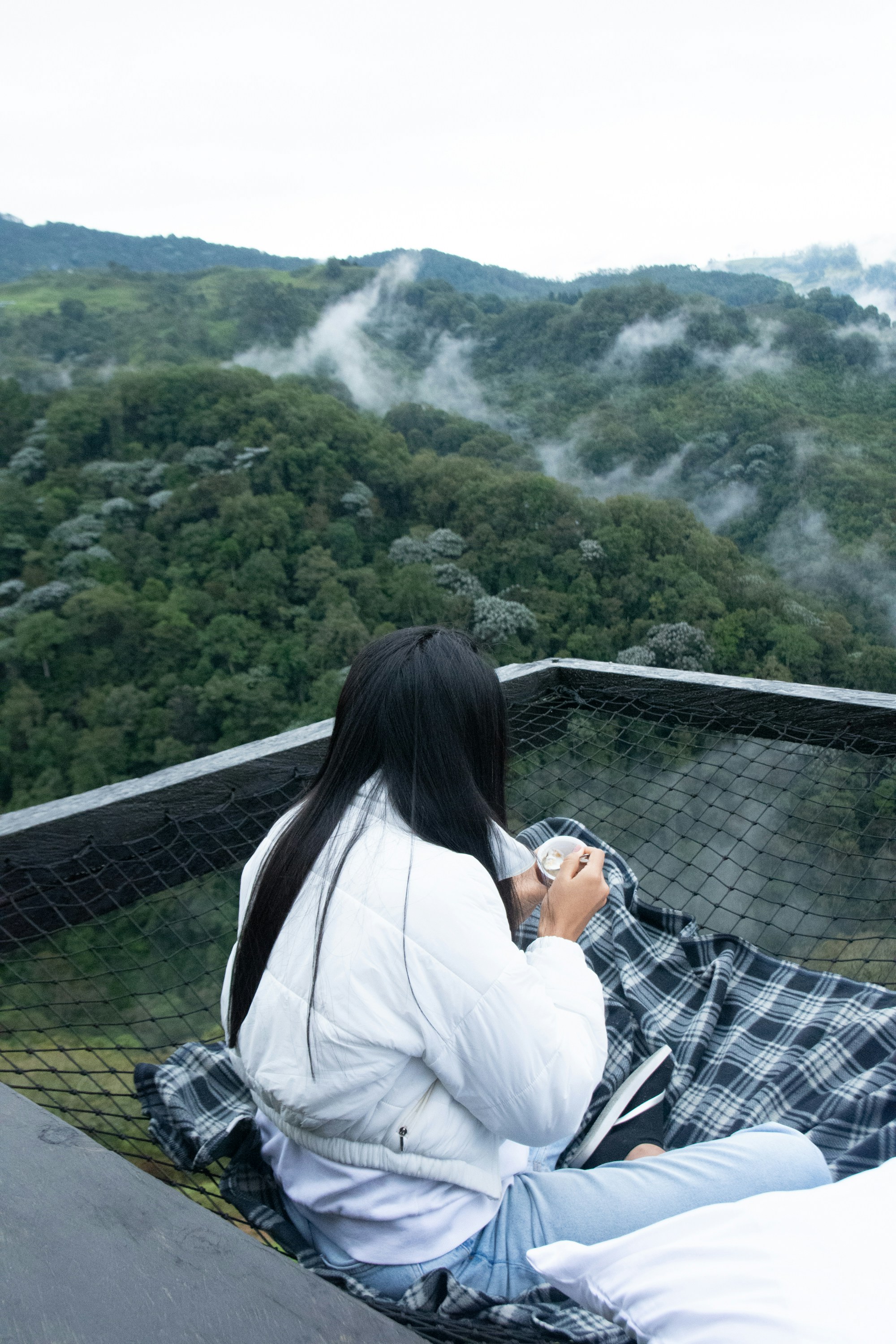 A woman sitting on top of a roof next to a forest