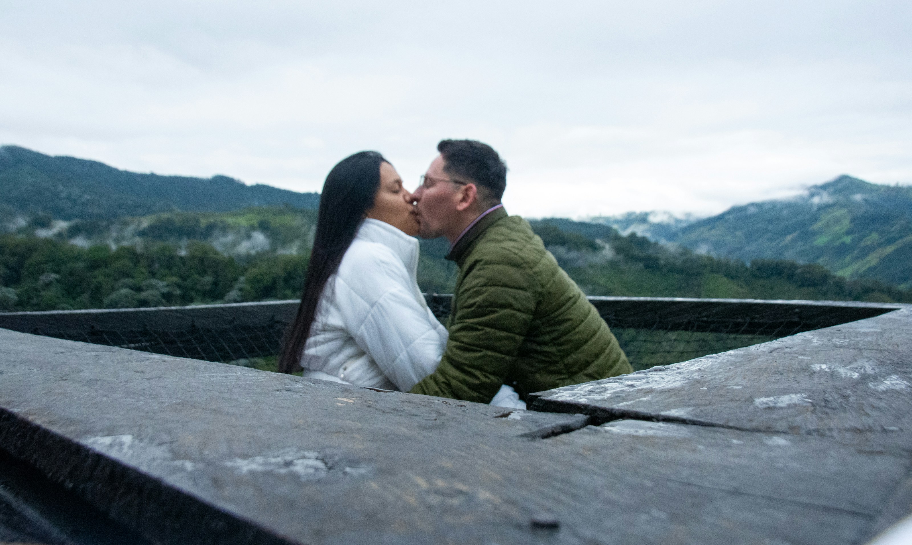 A man and a woman are kissing on a ledge