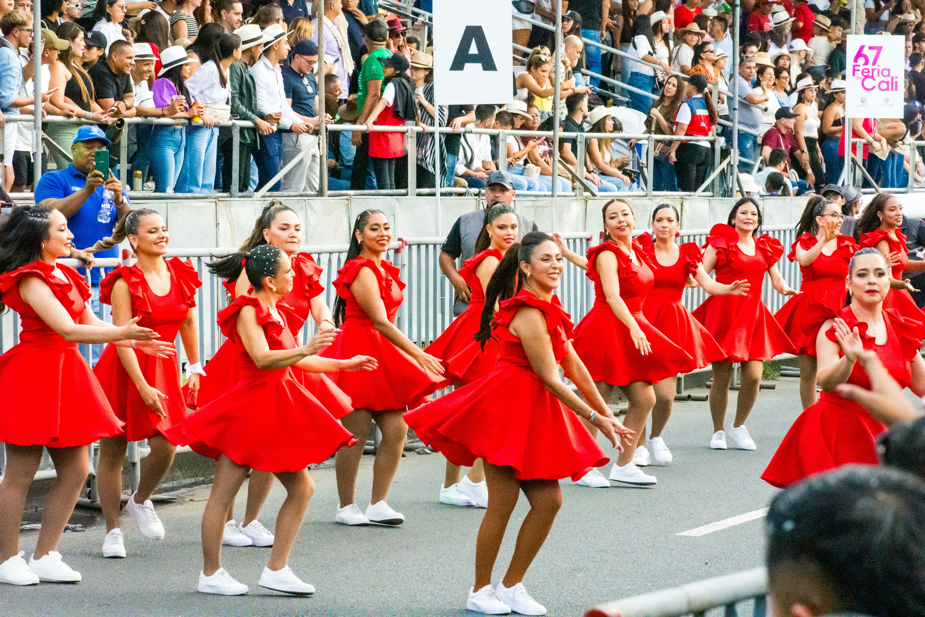 A group of girls in red dresses are dancing in a parade