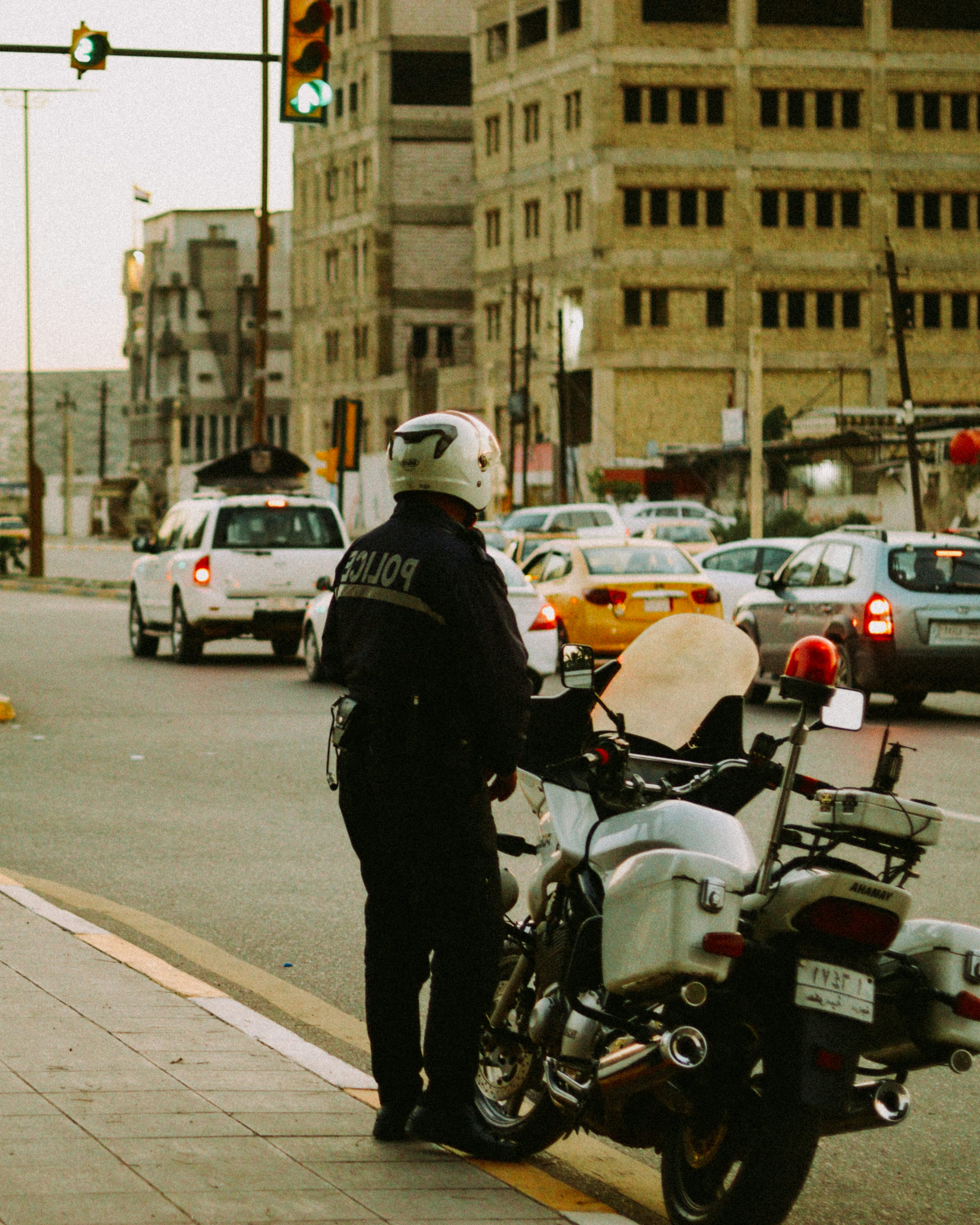 A police officer standing next to a motorcycle on a city street