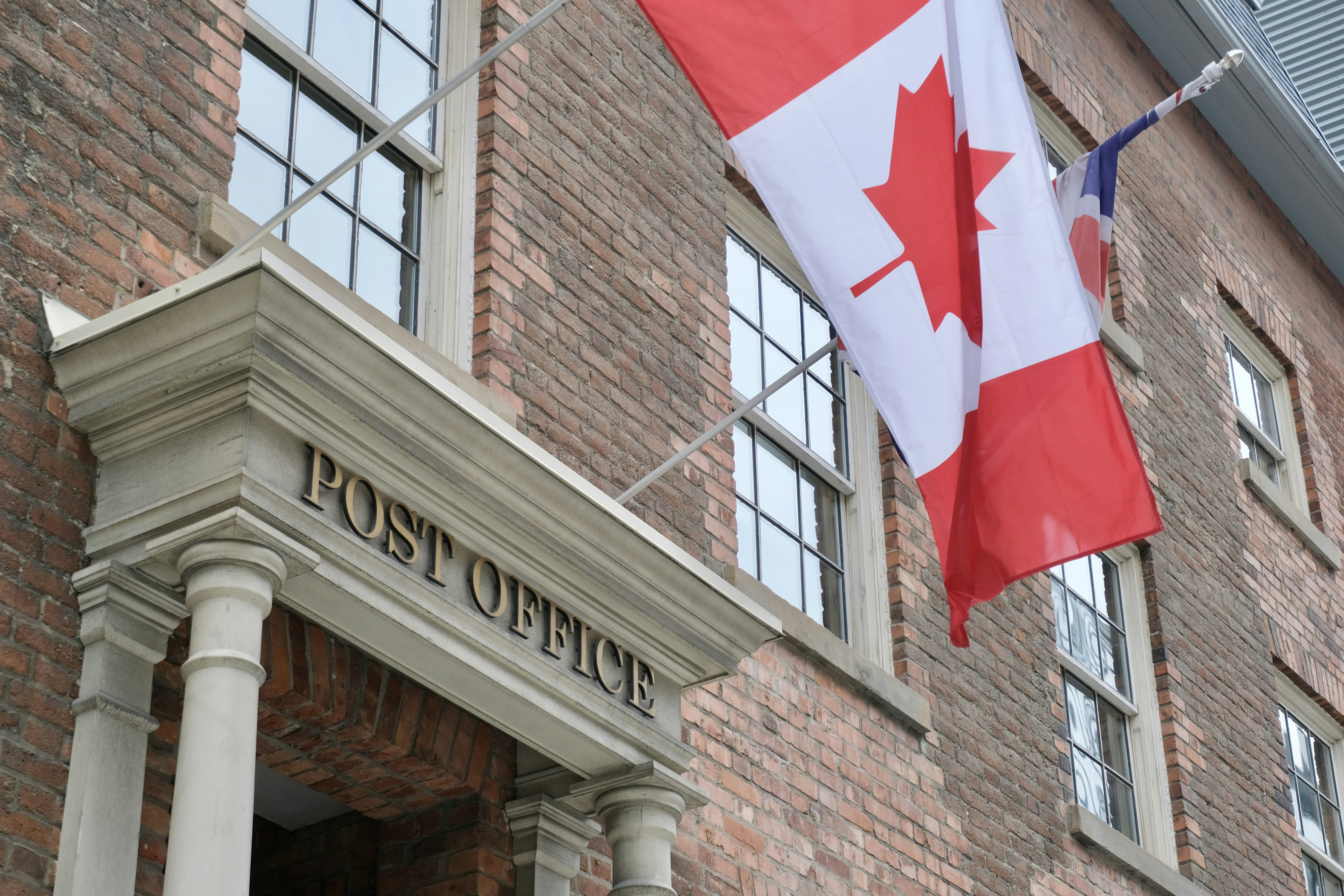 The canadian flag is flying outside of the post office