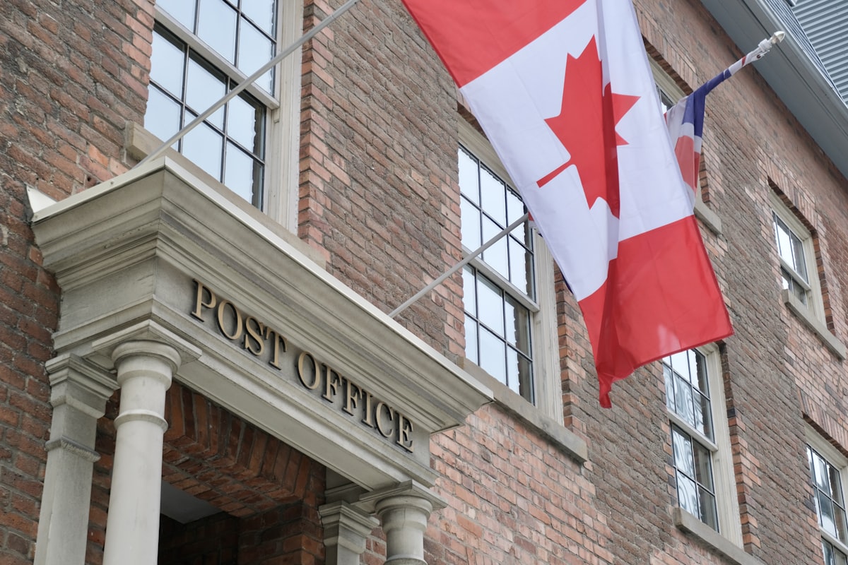 Canadian flag flying outside a heritage Canada Post building
