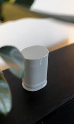 A white speaker sitting on top of a wooden table