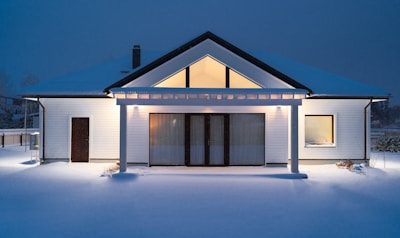 A house is lit up at night in the snow