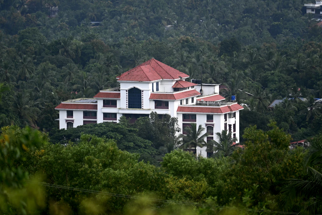 A white building with a red-tiled roof among green hills (sample photo)
