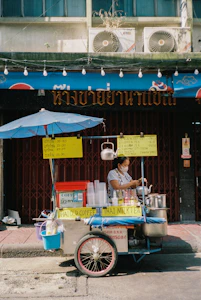 A man selling food from a cart on the side of the road