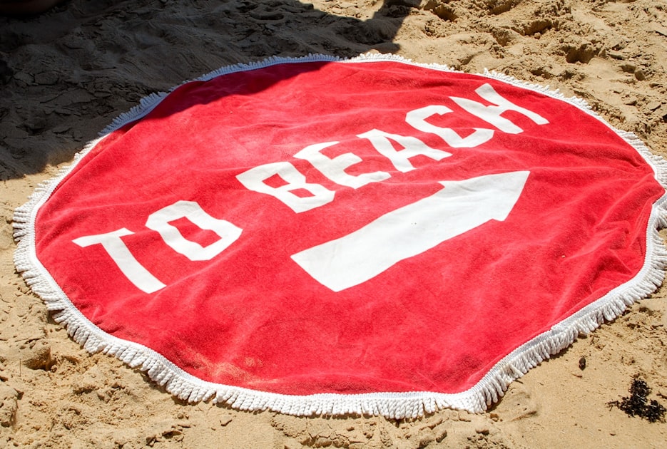 A round beach towel with the words beach written on it