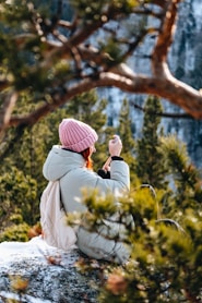 A woman sitting on a rock taking a picture