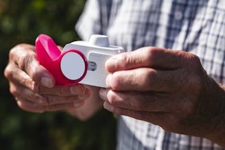 A man holding a camera with a pink object in his hand