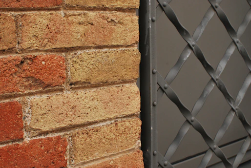 A close up of a brick wall with a metal gate