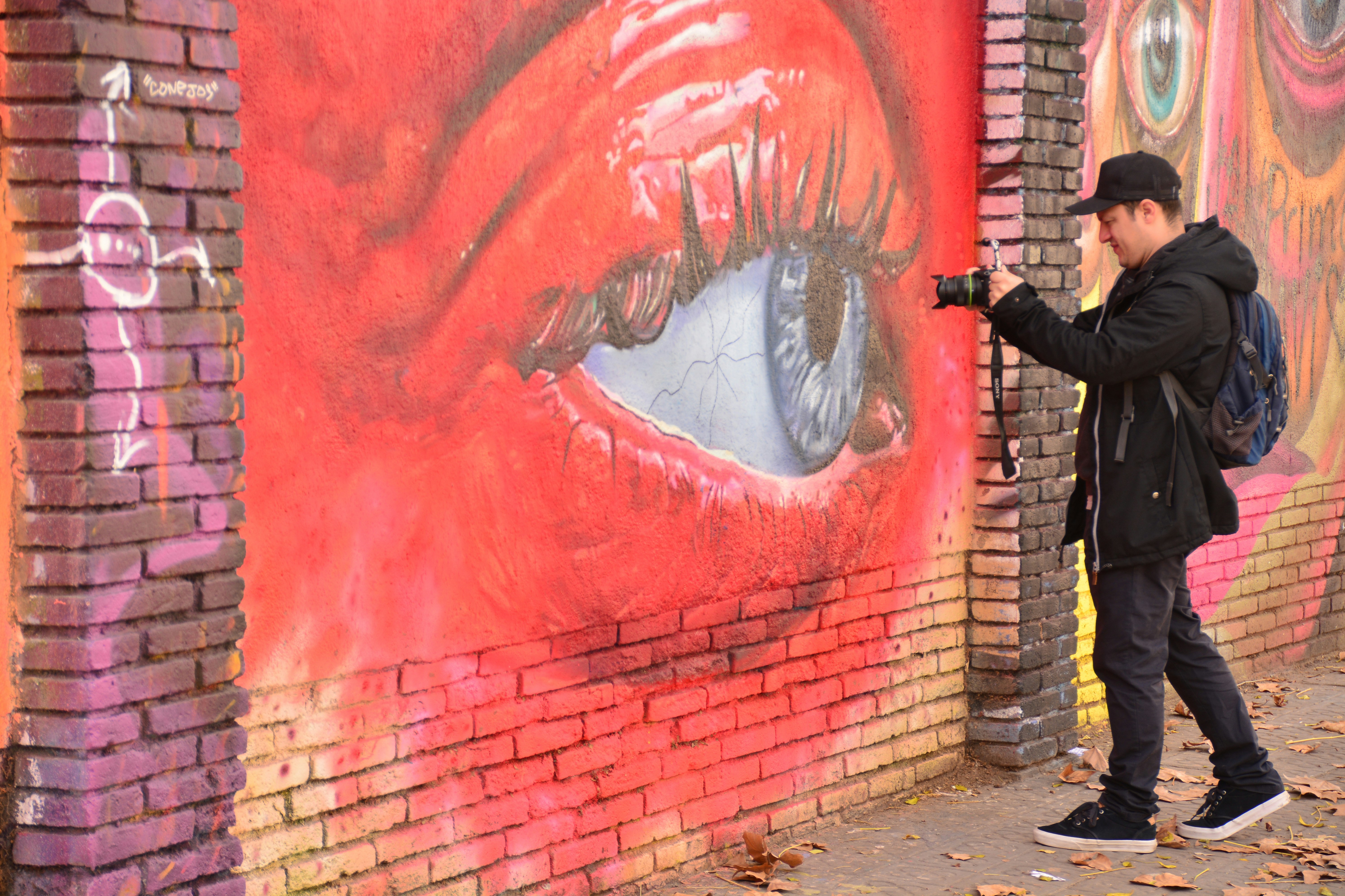 A man standing next to a brick wall with graffiti on it