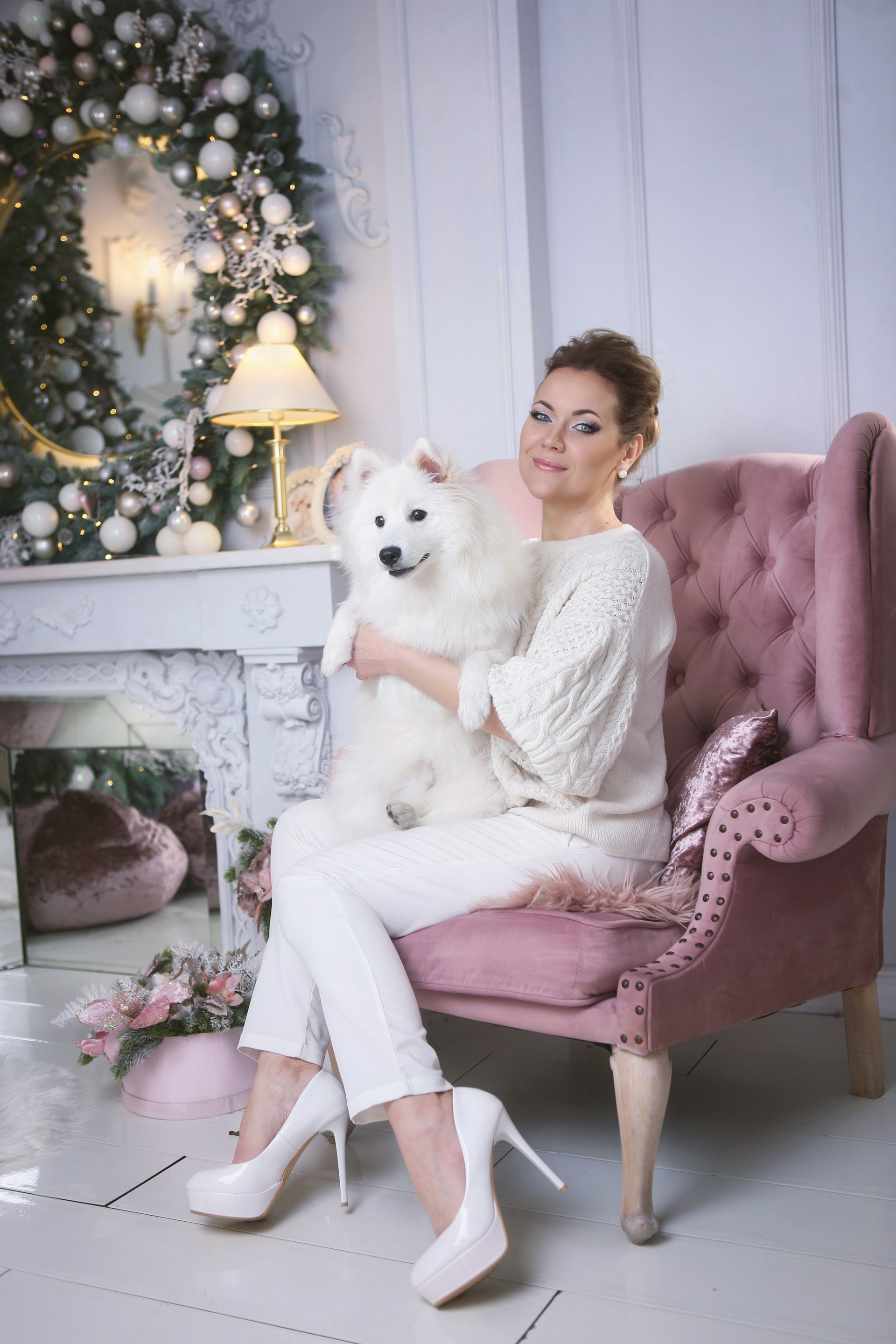 A woman sitting on a pink chair holding a white dog
