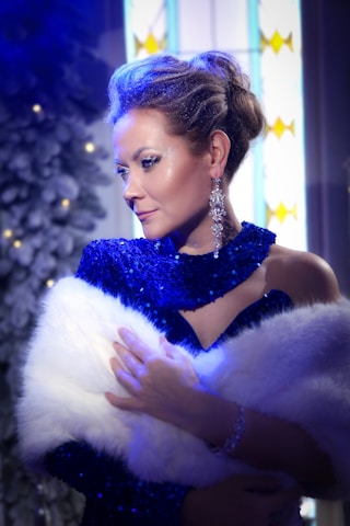A woman in a blue dress holding a white fur stole