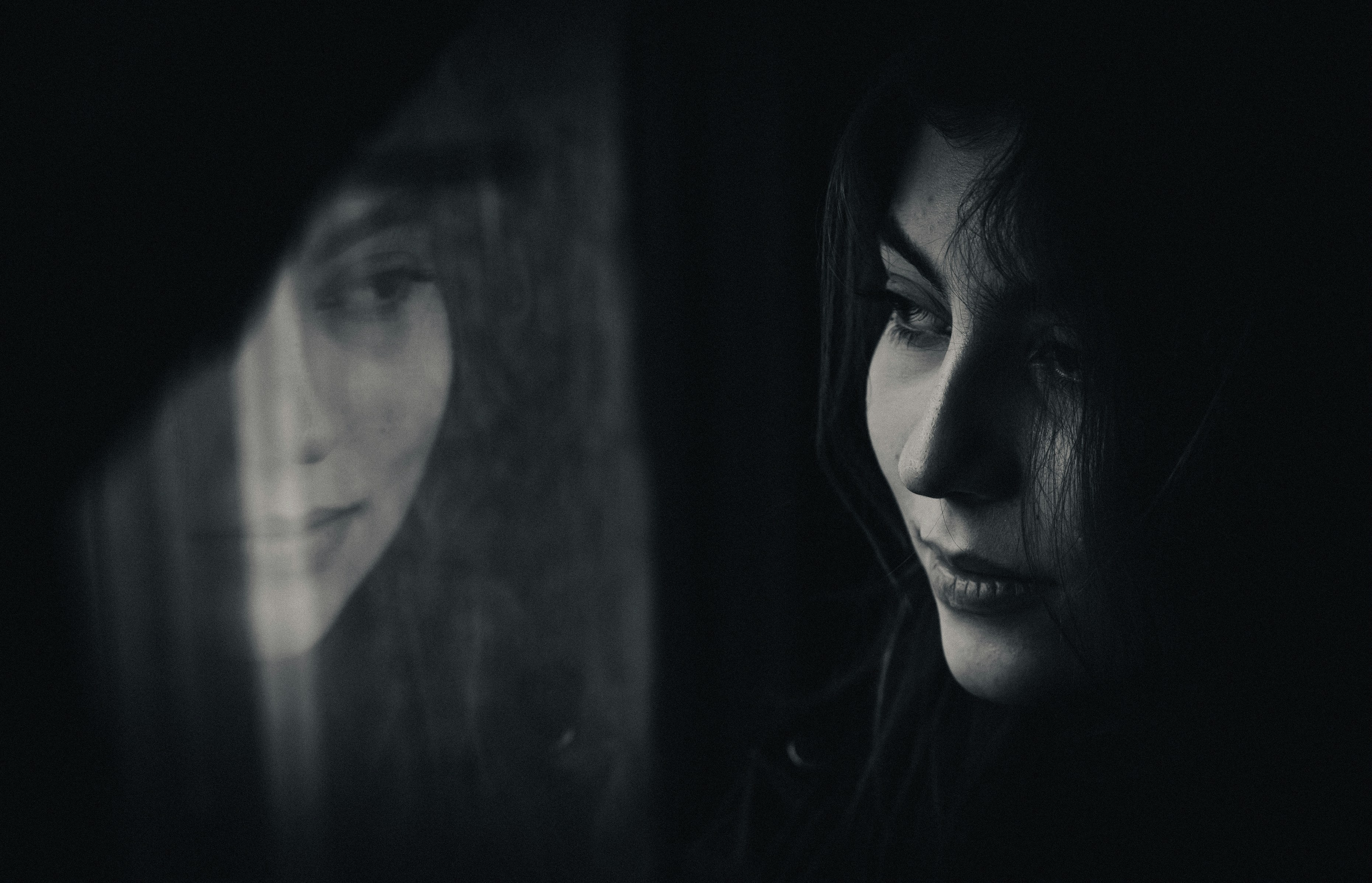 A black and white photo of a woman looking out a window
