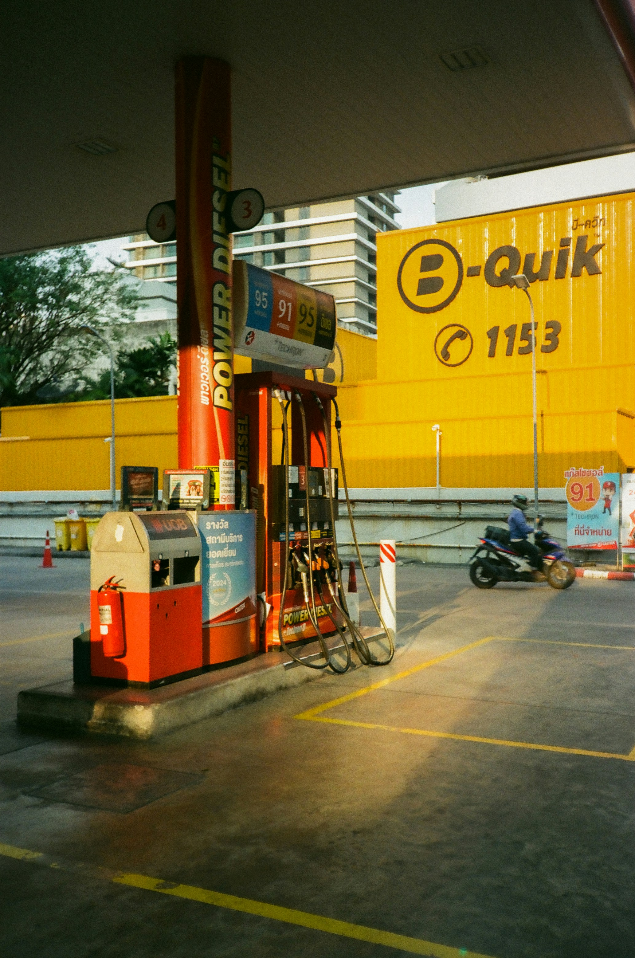 Sebuah pompa bensin dengan bangunan kuning di latar belakang
