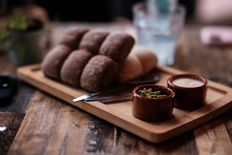 A wooden cutting board topped with food on top of a wooden table