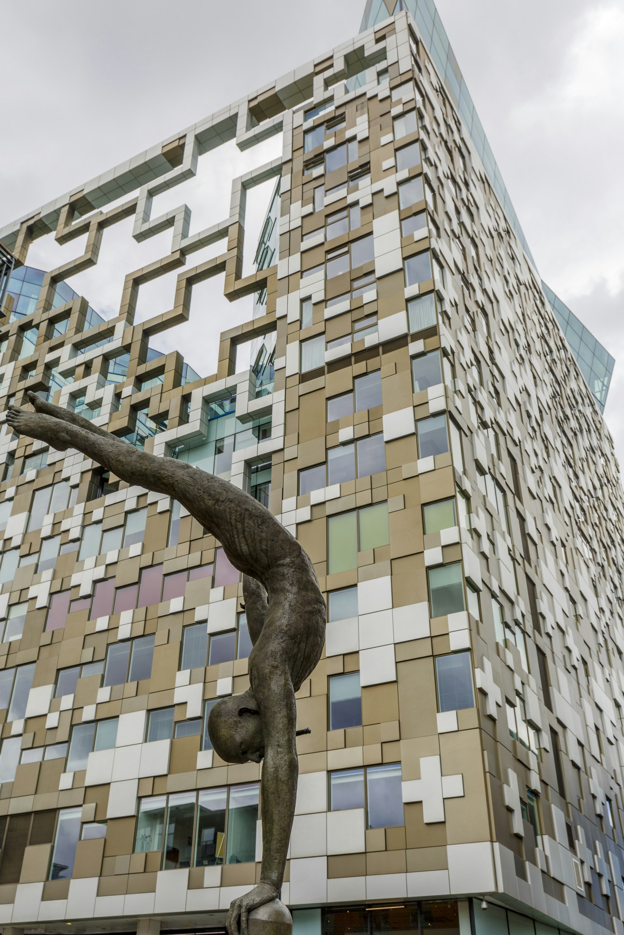 A statue of a man doing a handstand in front of a building