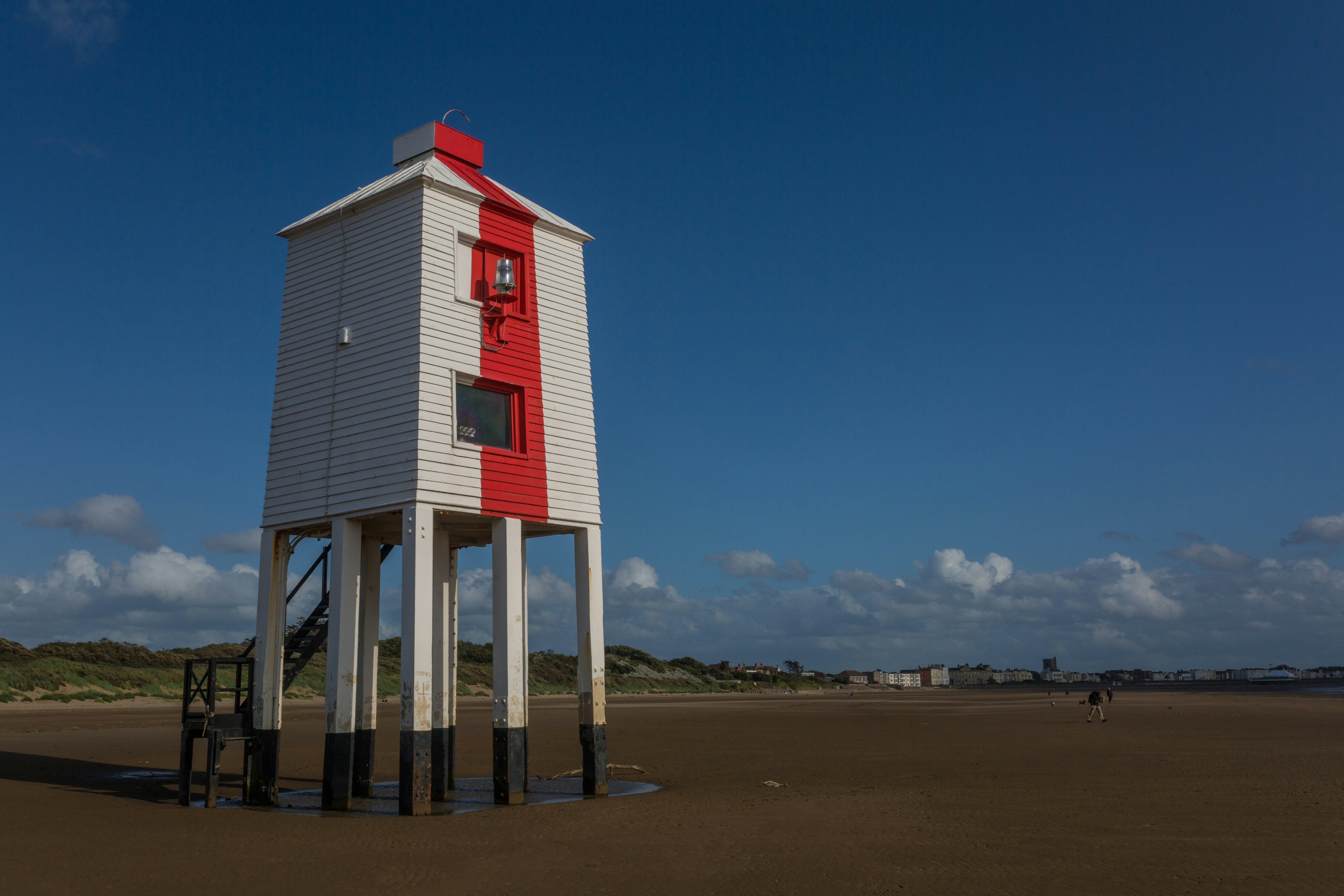 A red and white tower sitting on top of a sandy beach
