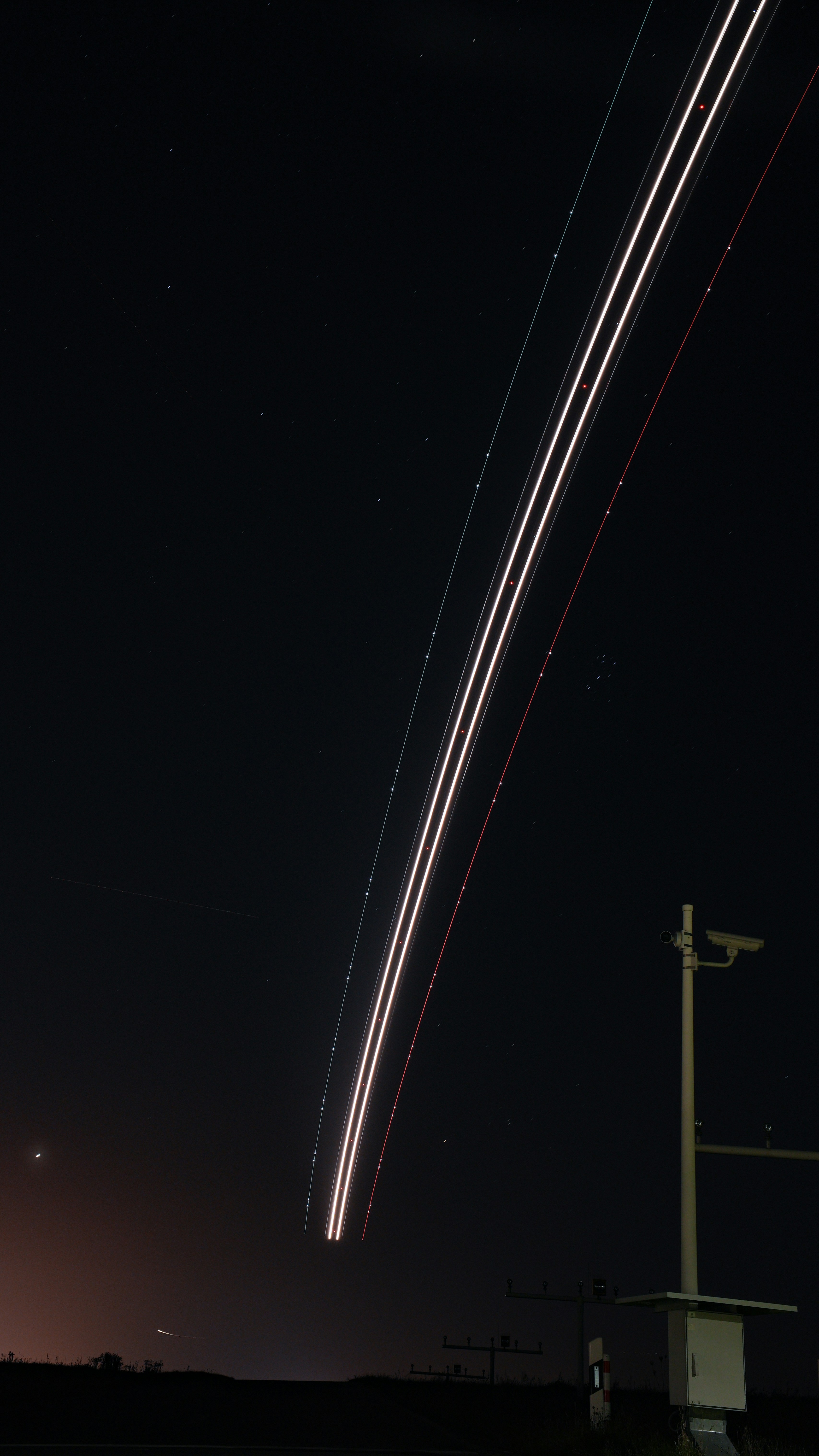 A long line of airplanes flying in the night sky