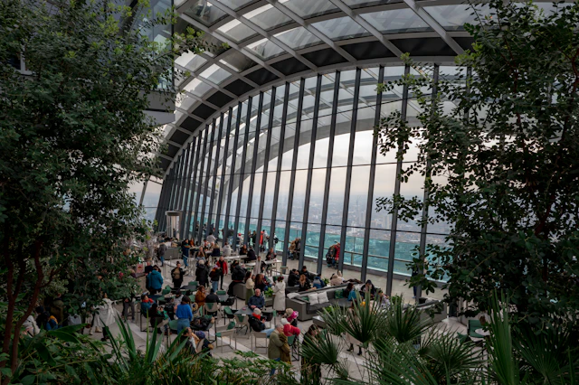 The ribbed glass atrium of Sky Garden with visitors seated among terrace plantings overlooking the city.