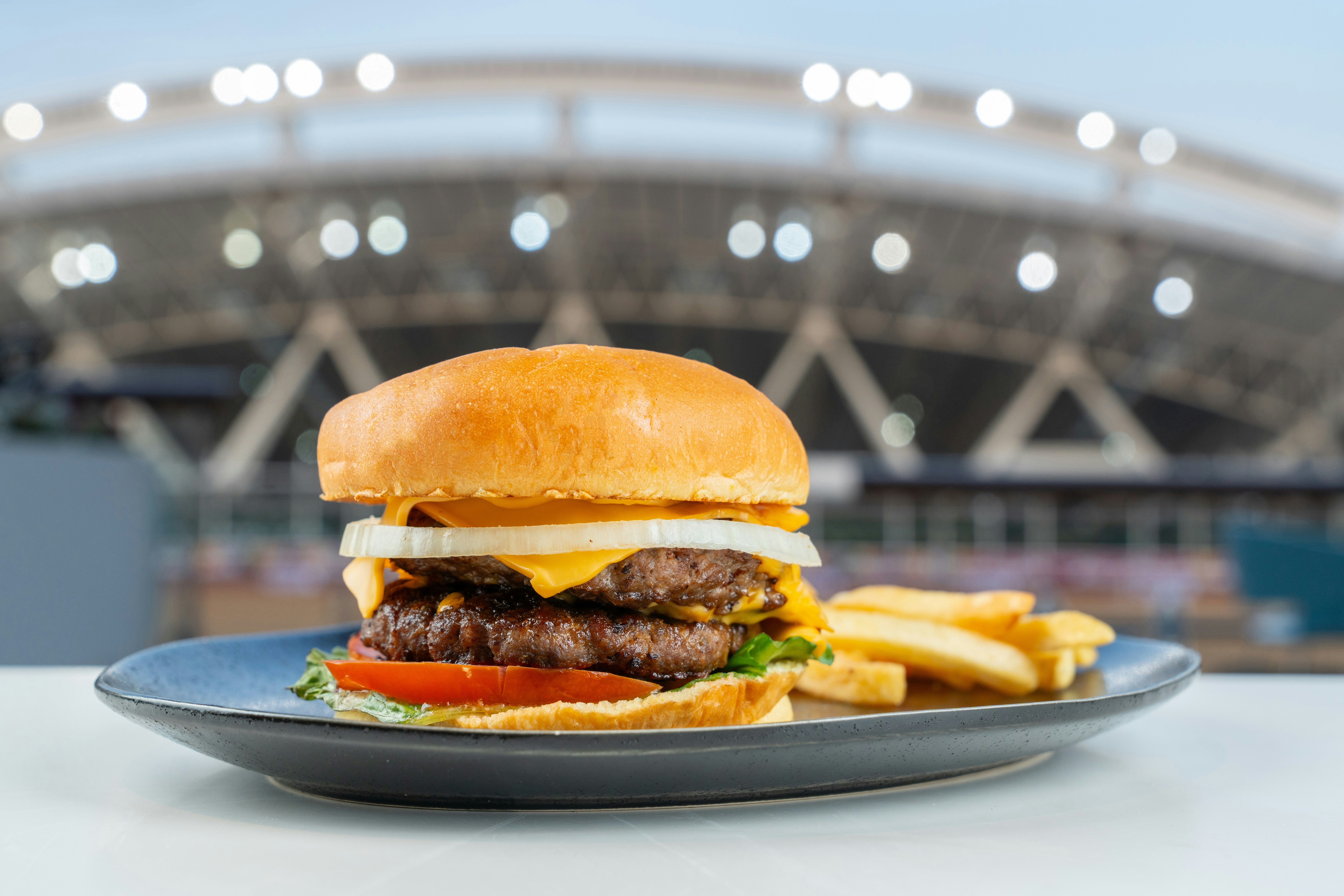 A hamburger and fries on a plate in front of a stadium