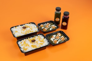 Four containers of food on an orange surface