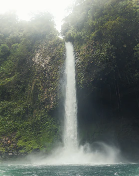 A large waterfall is in the middle of a body of water