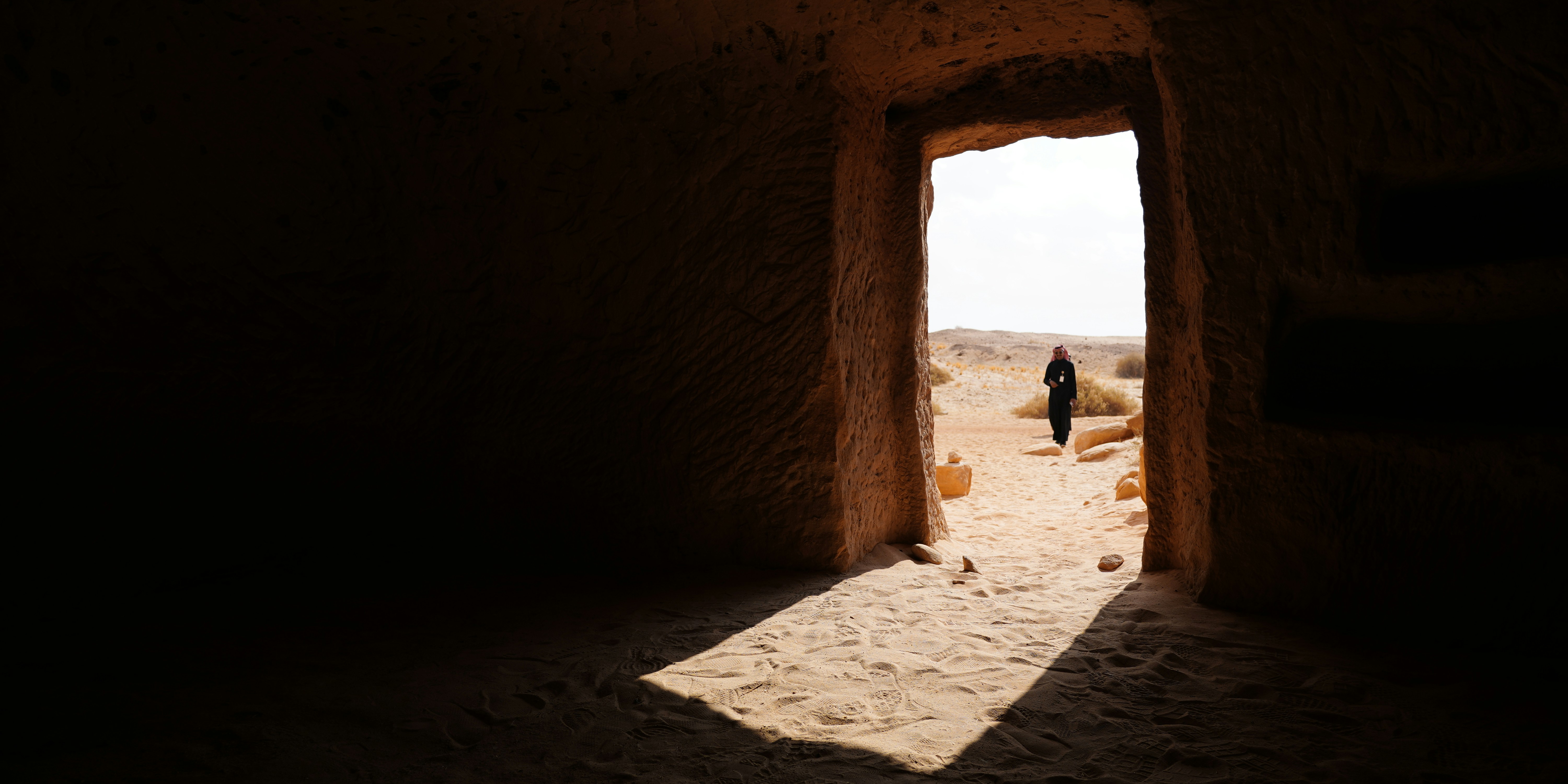 A person standing in an open doorway in a desert