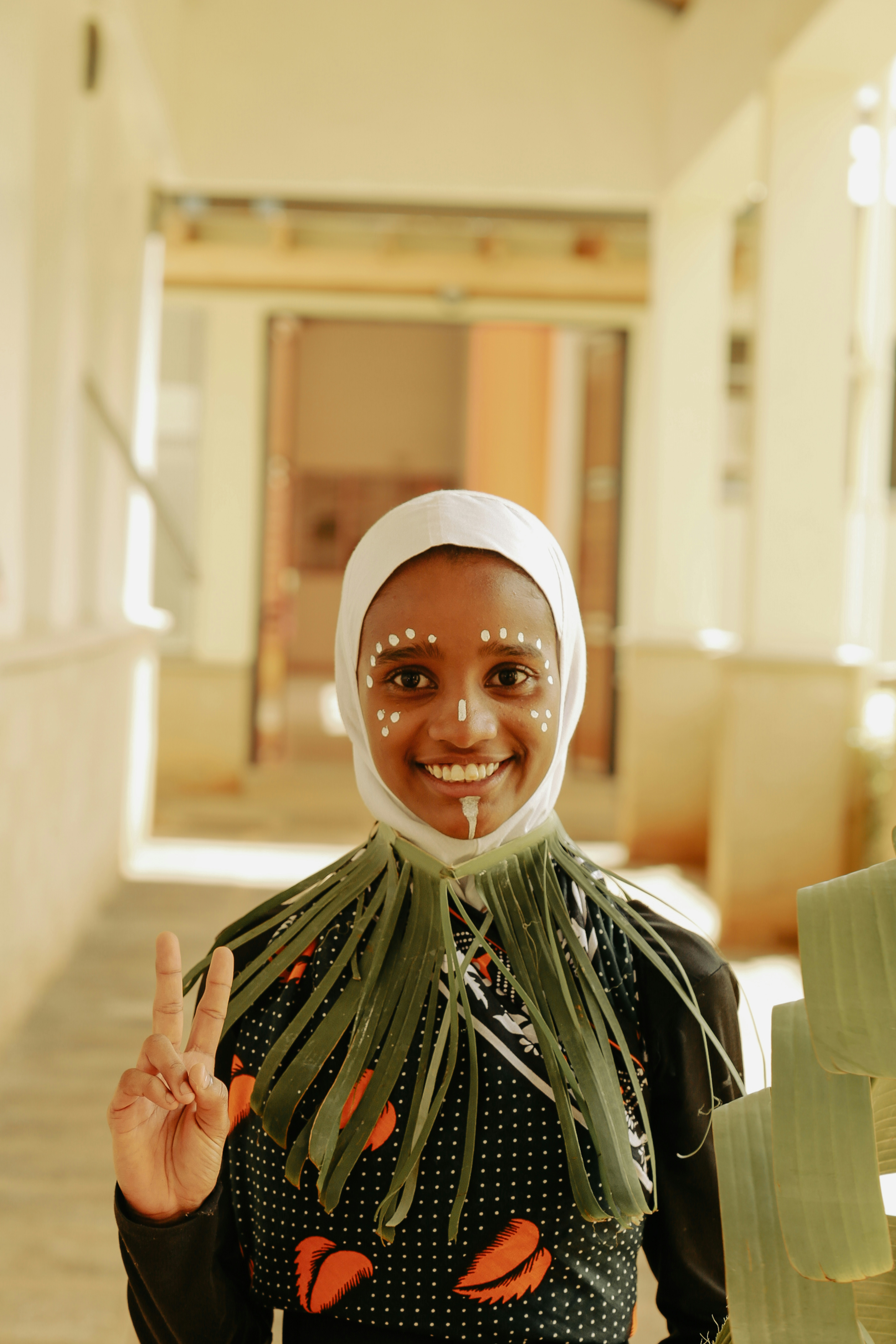 ピースサインを掲げるヒジャブ姿の女性