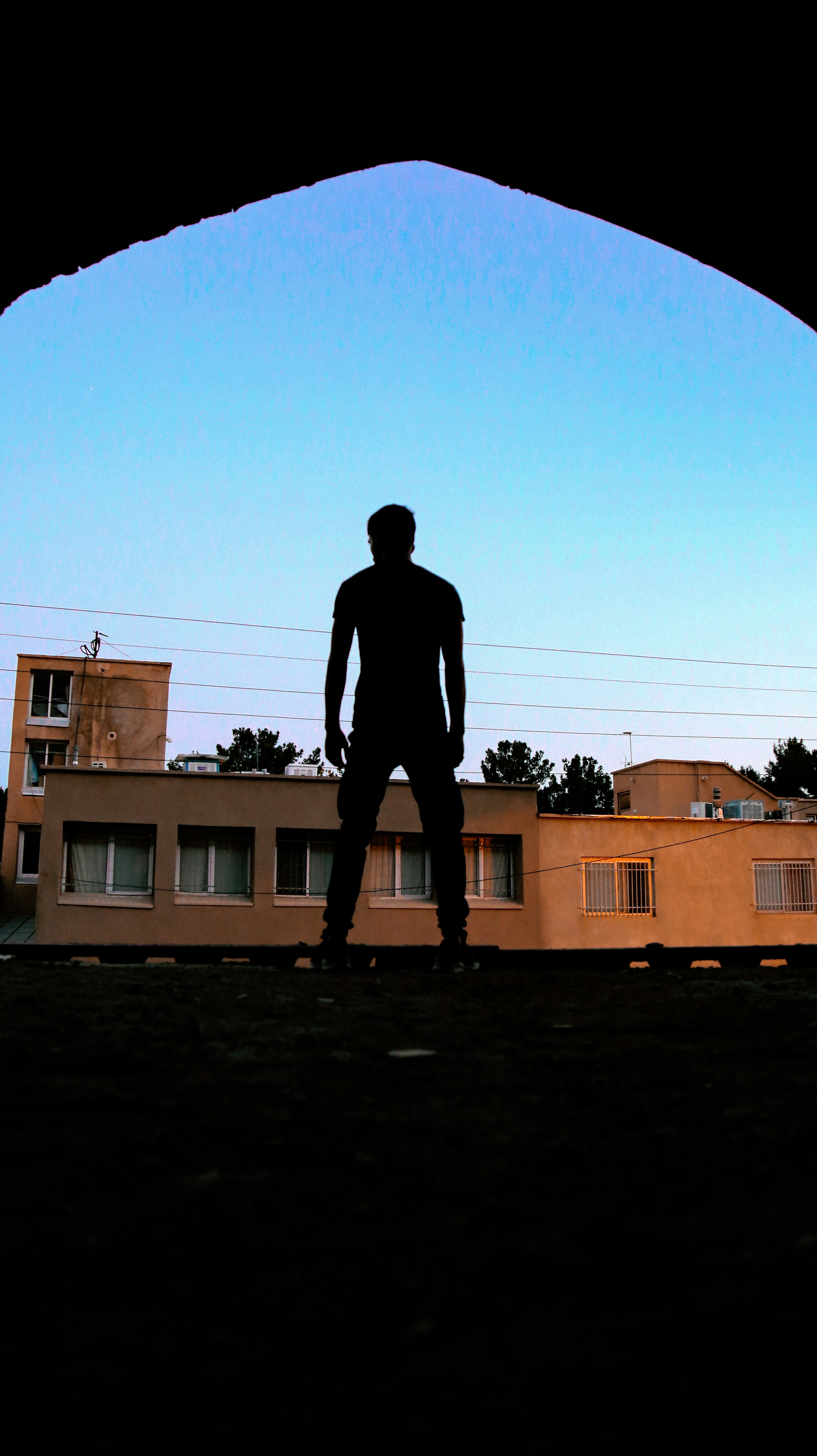 A silhouette of a man standing in front of a building