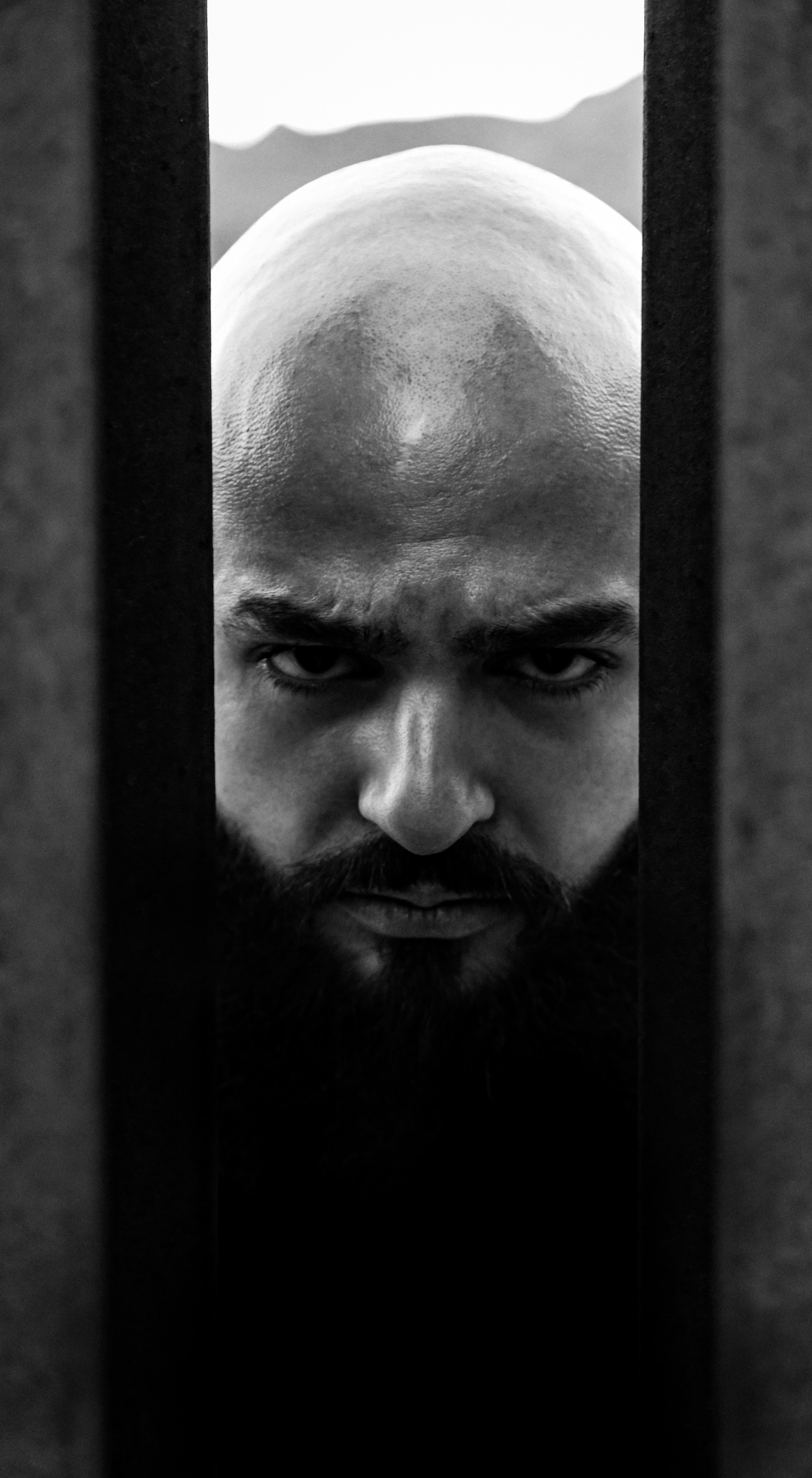 A man with a bald head looking through a doorway