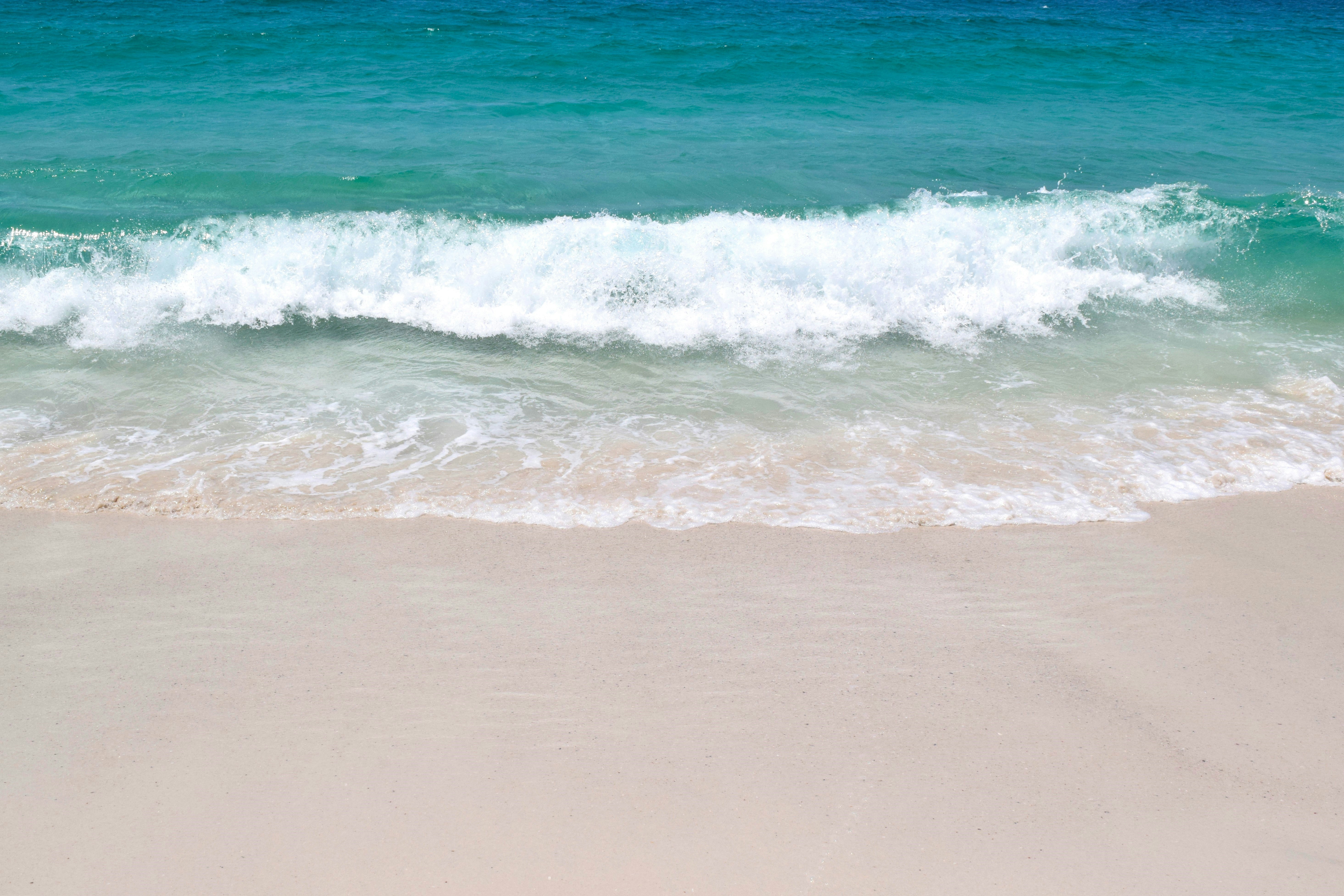 A sandy beach with a wave coming in to shore