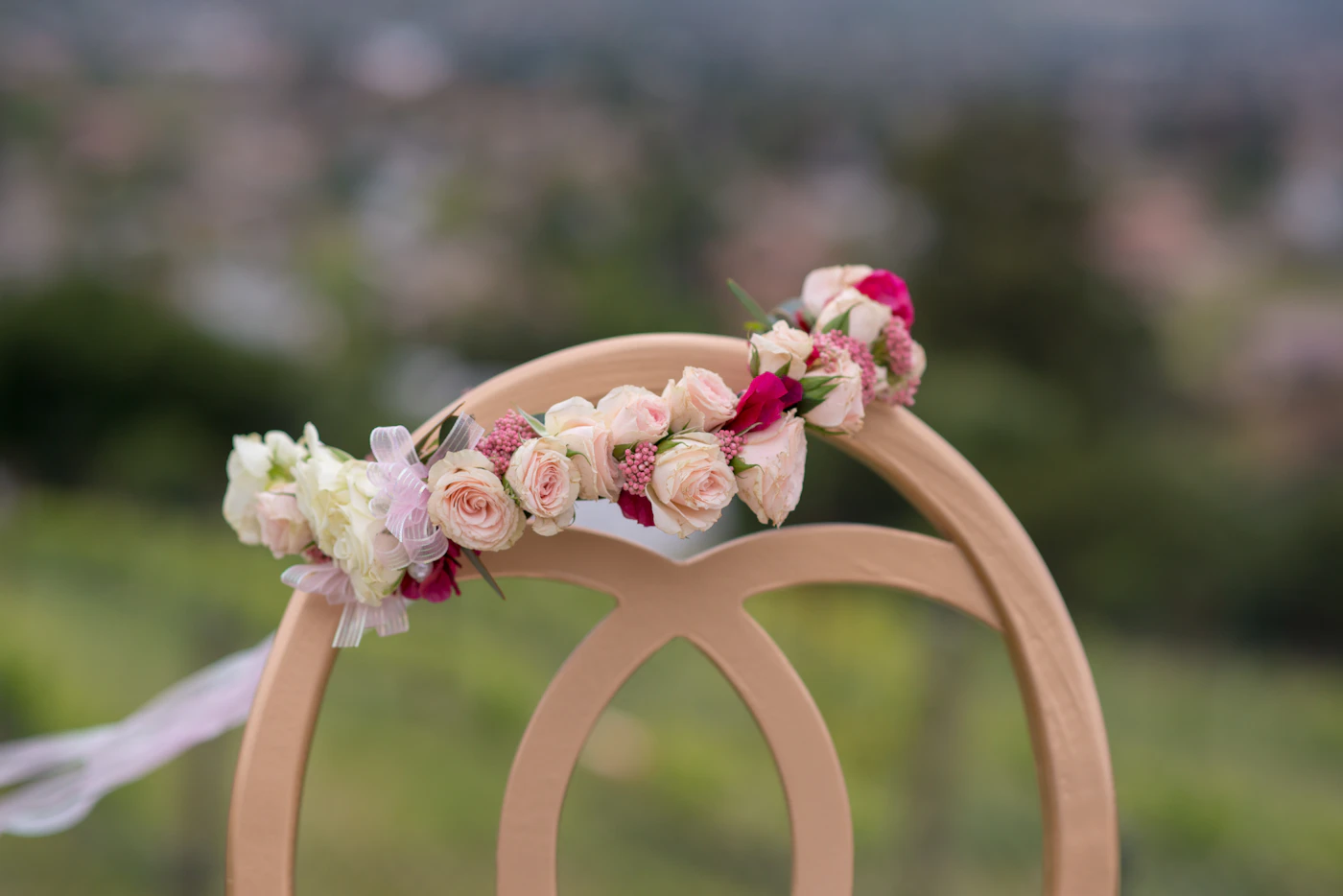 DIY flower crowns for bridesmaids — A bridesmaid's hand holds a delicate DIY flower crown made of roses and baby's breath.