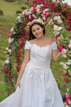 A woman in a wedding dress standing under a floral arch