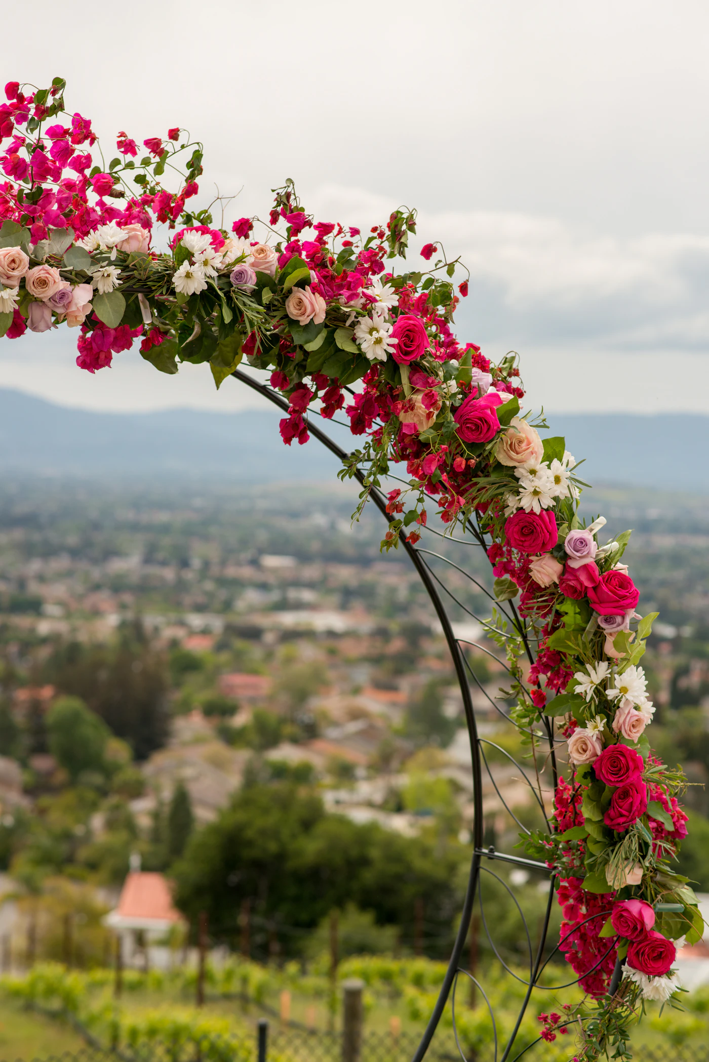 DIY wedding arch ideas with fresh flowers — A lush arch draped in eucalyptus and white roses frames the couple at the altar.