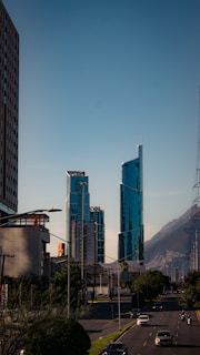 A city street with tall buildings and a mountain in the background