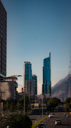 A city street with tall buildings and a mountain in the background